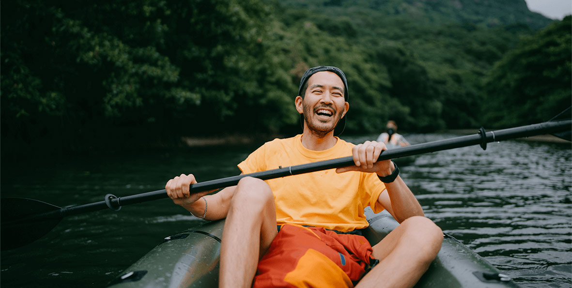 A man enjoying himself as he rows a boat on a river.