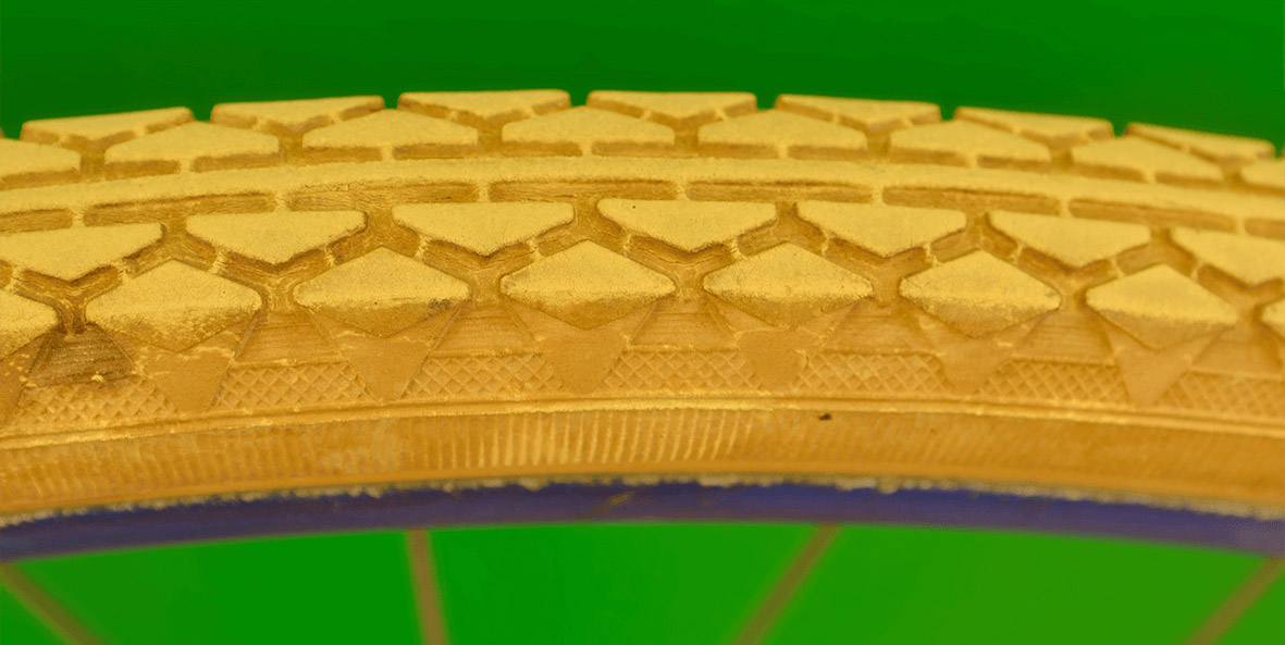 A close-up of a golden tire on green background.
